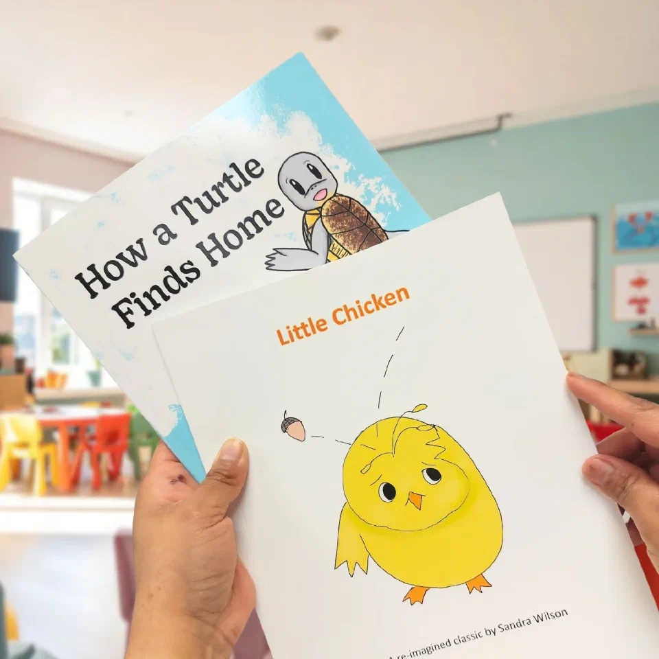 Two printed children’s picture books held up in a classroom