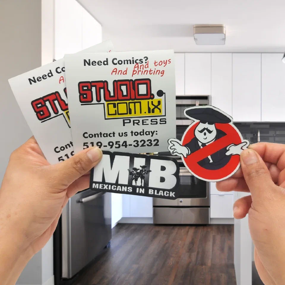 Printed fridge magnets held in two hands, including two die-cut character magnets