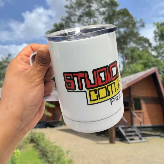 A branded travel mug printed with the Studiocomix Press logo